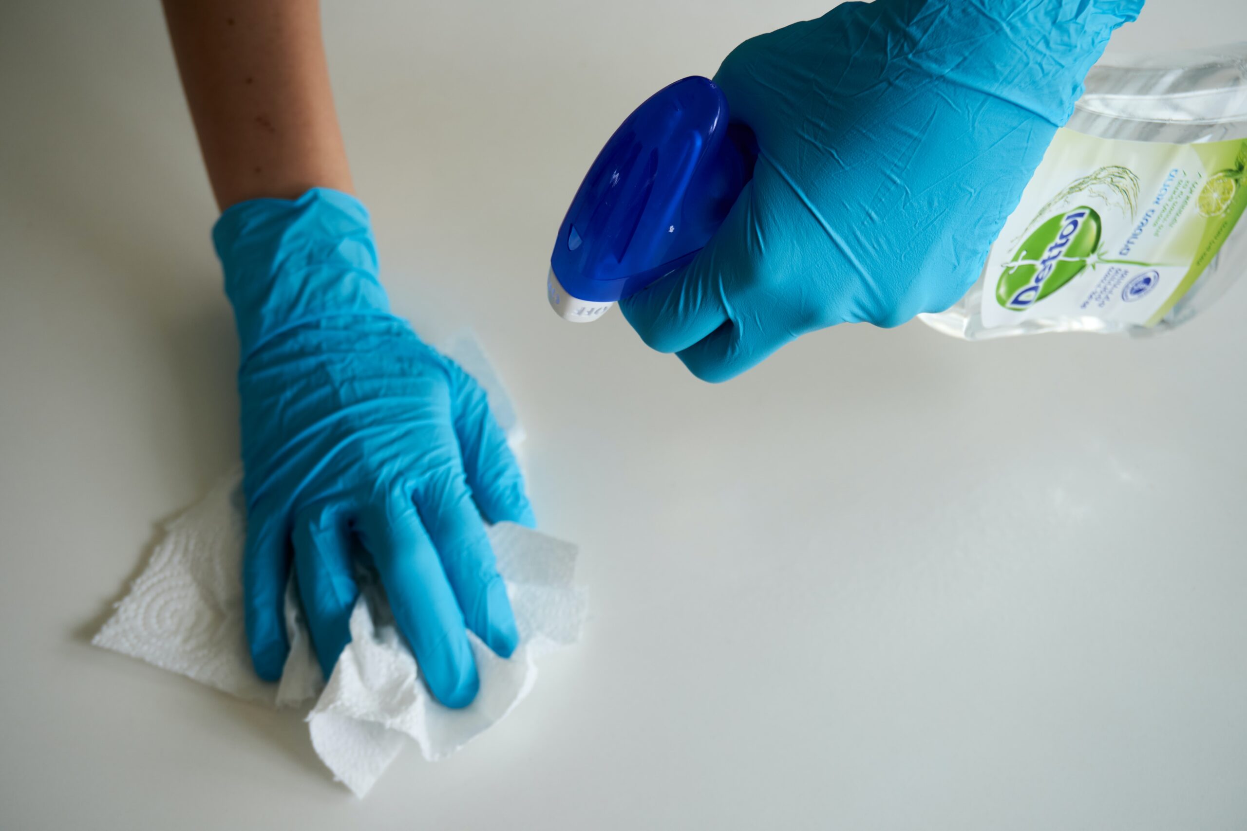 Hands with gloves cleaning a dirty surface.