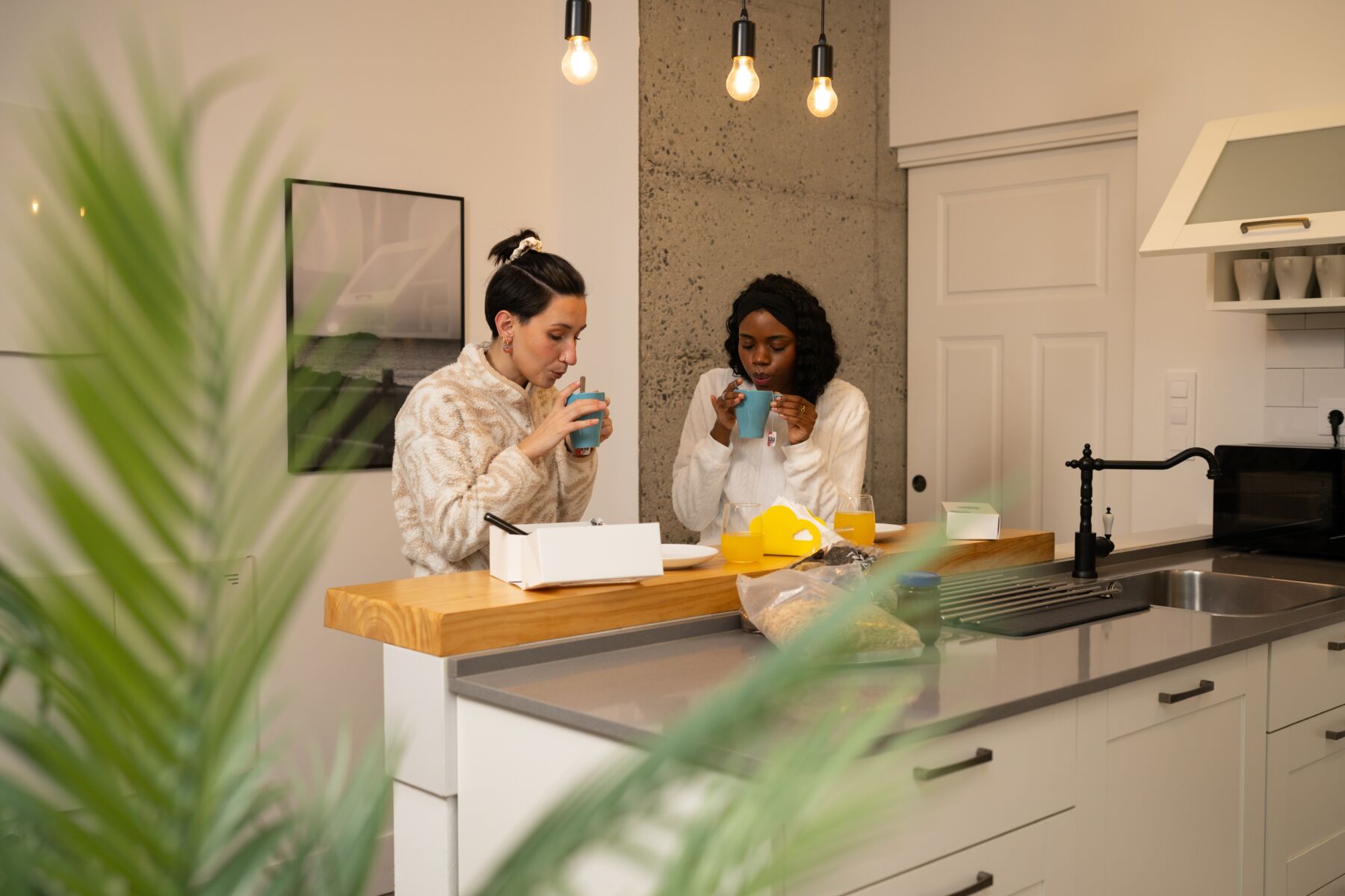 Two young women sit in a kitchen.