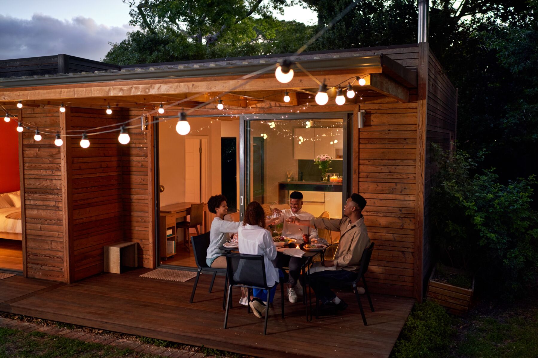 A young group of people eat dinner on their patio.