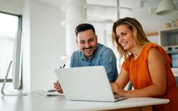 A couple sit at a computer.