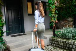 Photo shows oman moving into a PadSplit coliving home with suitcase.