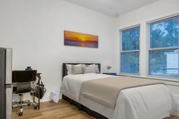 A white bedroom with a bed and desk.