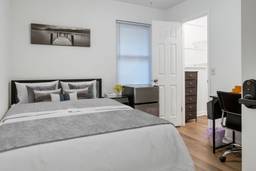 A bedroom with a large queen bed and a mini fridge.