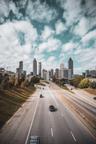 View of Atlanta, Georgia skyline with tall office buildings and apartments. A road leads you there.