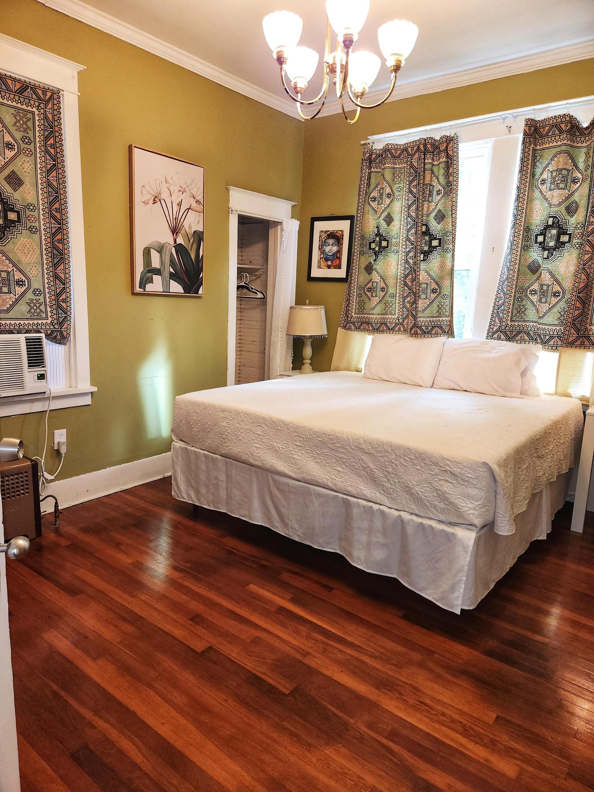 Green room. Courtyard view with 3 windows, King bed, wood floor, window AC/Heat unit, dedicated work station and TV