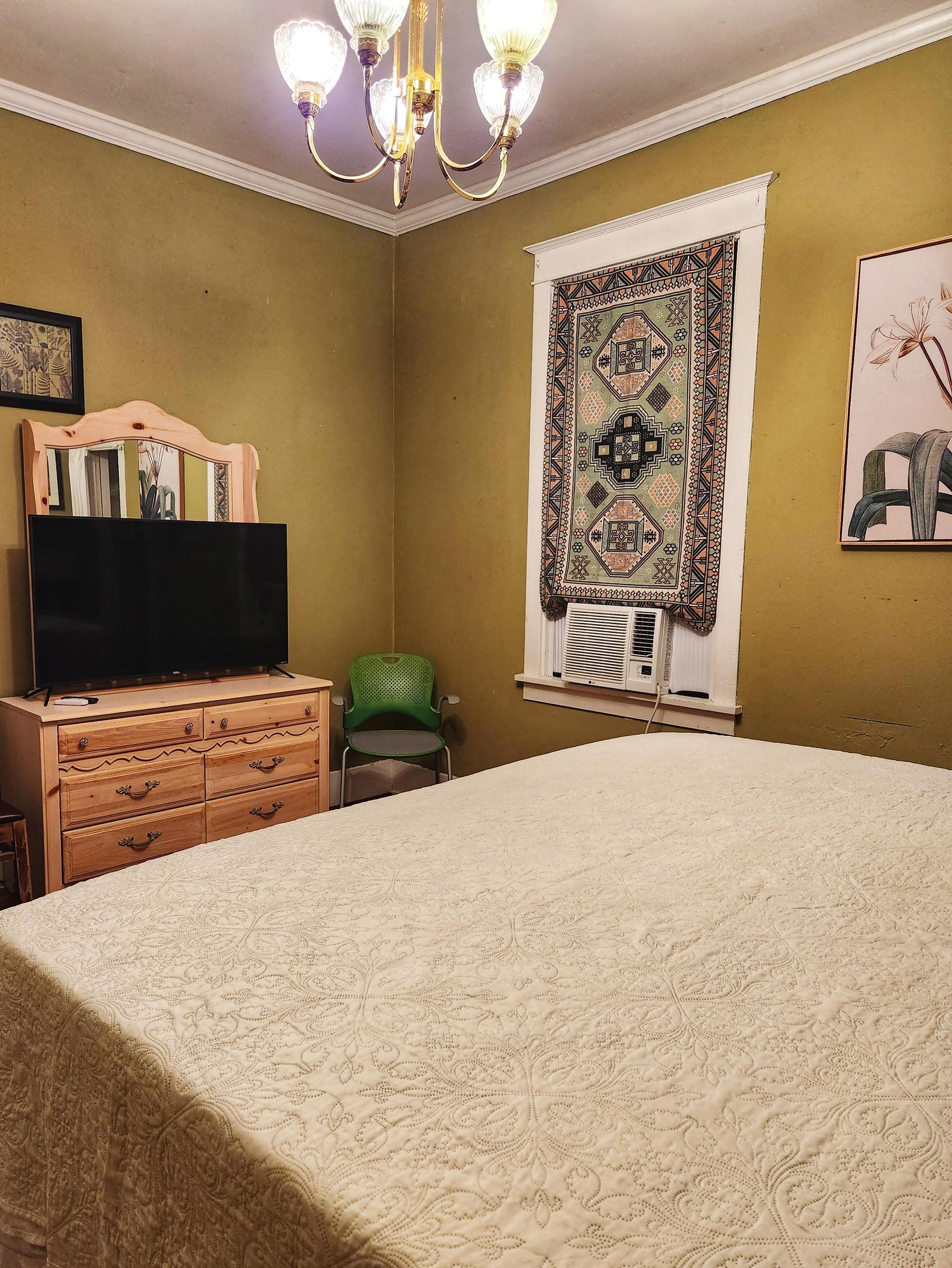 Green room. Courtyard view with 3 windows, King bed, wood floor, window AC/Heat unit, dedicated work station and TV