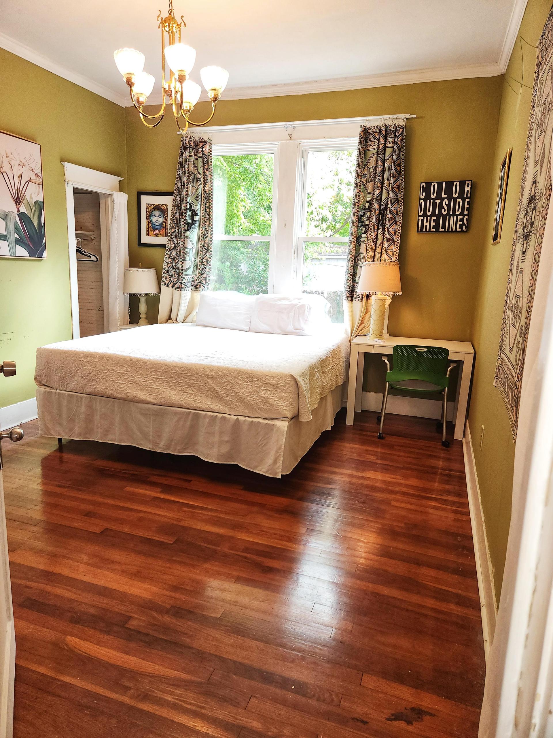 Green room. Courtyard view with 3 windows, King bed, wood floor, window AC/Heat unit, dedicated work station and TV