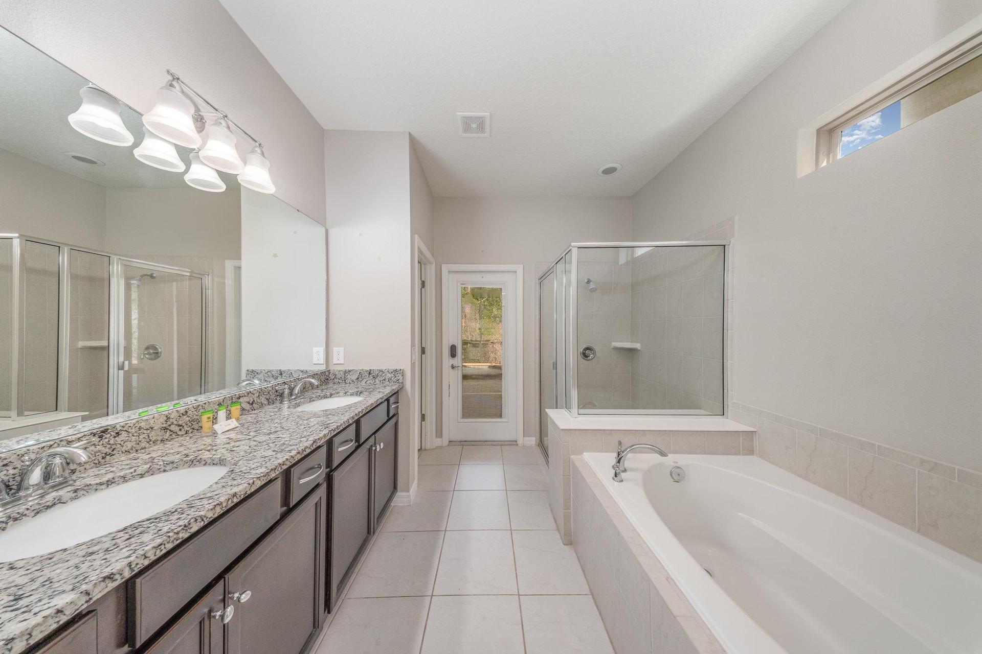 Pamper yourself in this luxurious bathroom featuring a spacious walk-in shower, soaking tub, double-sink and granite vanity.