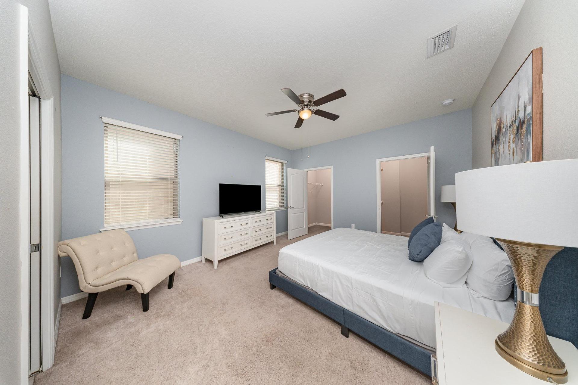 Unwind in this spacious master suite featuring a plush king bed, cozy lounge chair, Smart TV, and  two walk-in closets