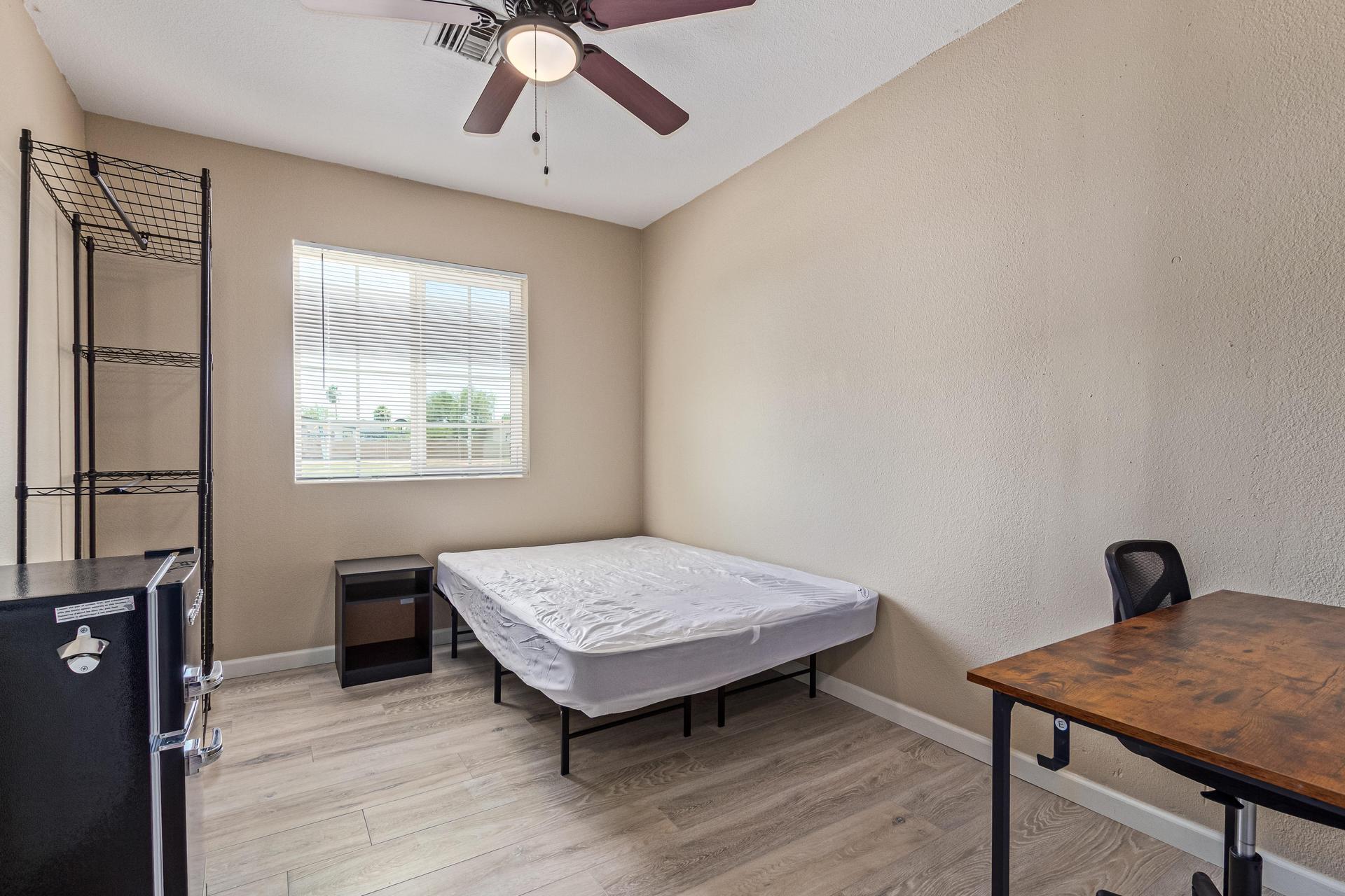 Full size bed, workspace/desk and office chair, mini fridge/freezer and closet rack