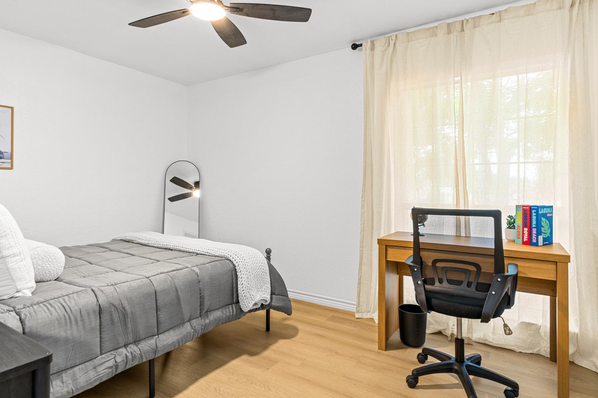Large room with workspace, closet and nightstand.