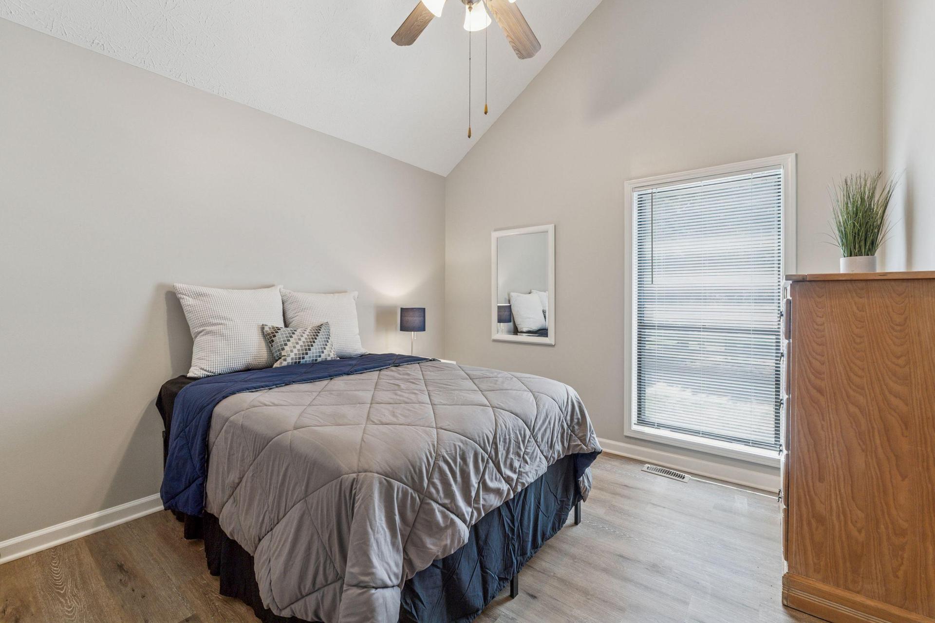 Room with vaulted ceilings, mirror, dresser, ceiling fan.