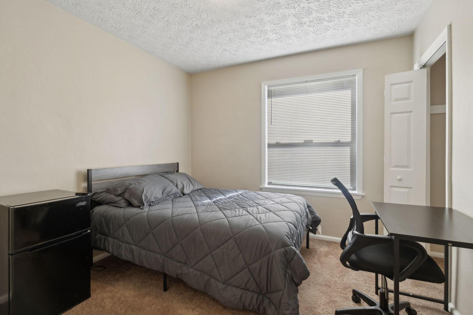 Bedroom features mini-fridge, writing desk and chair