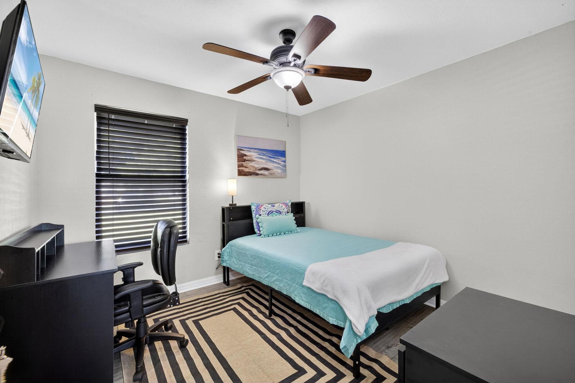 Bedroom 1 featuring a full-size bed, desk & wall-mounted television
