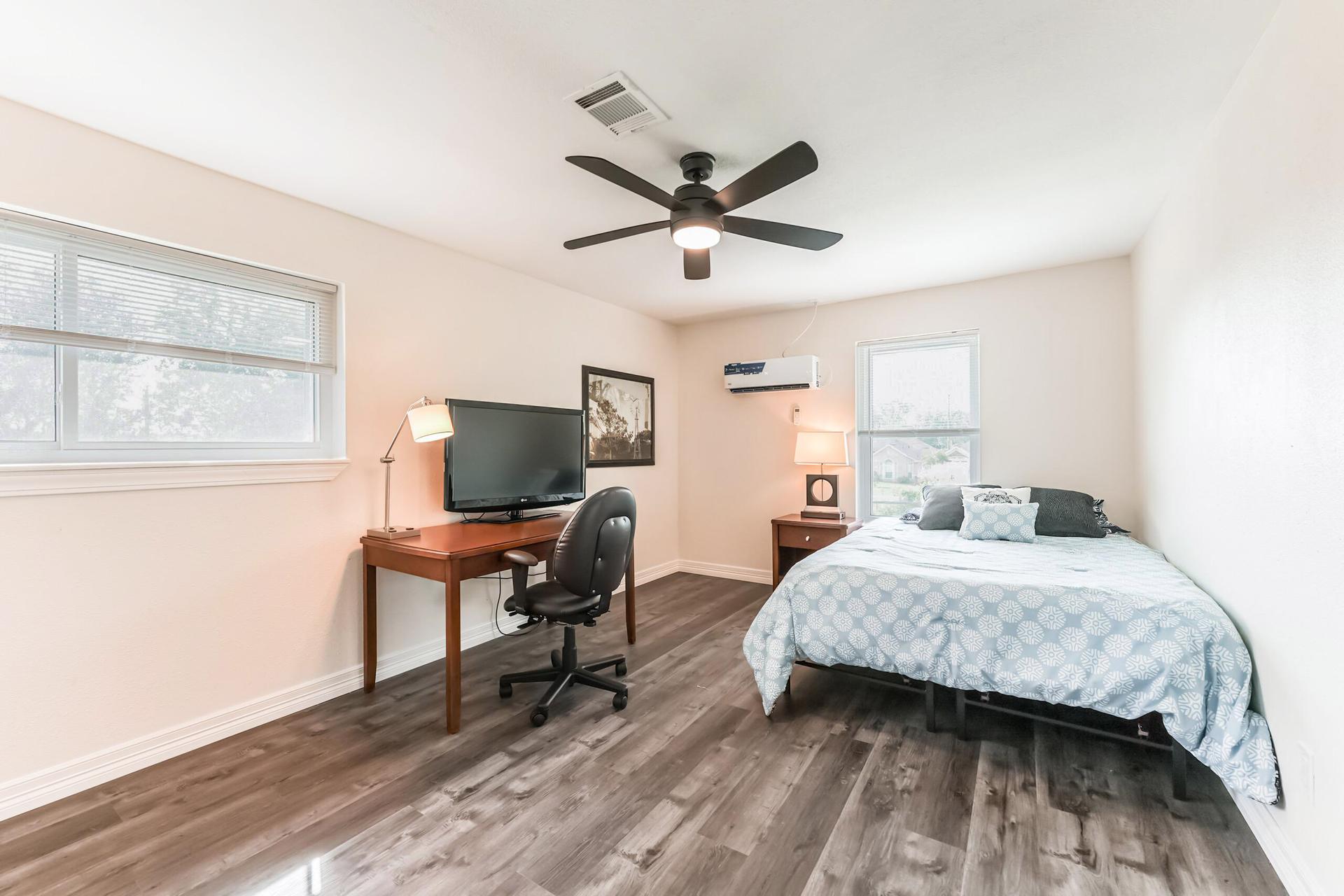 Upstairs room with minisplit AC, queen bed, hybrid mattress, night stand, full length mirror, and desk with chair and TV.