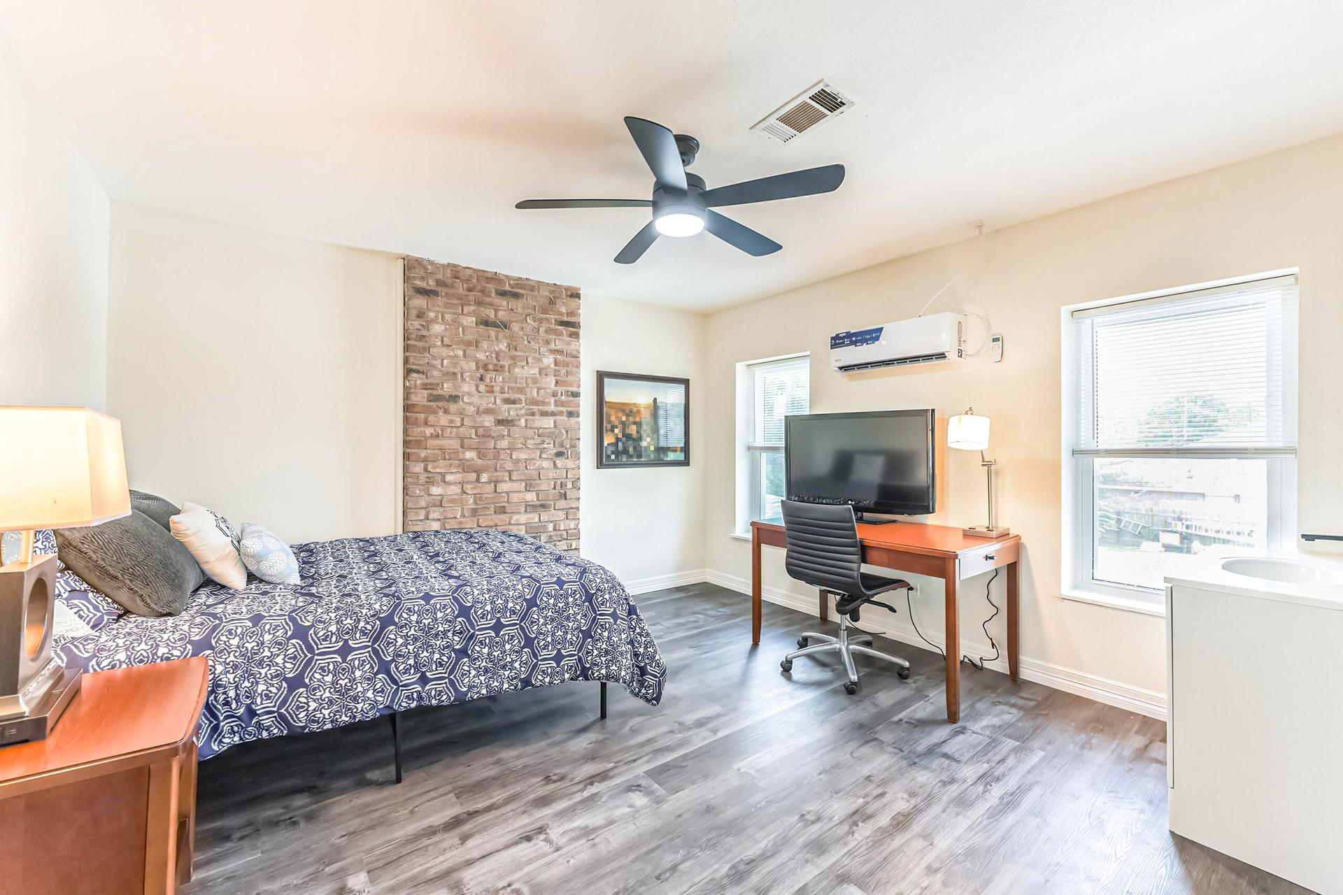 Upstairs room with minisplit AC, queen bed, hybrid mattress, night stand, full length mirror, and desk with chair and TV.