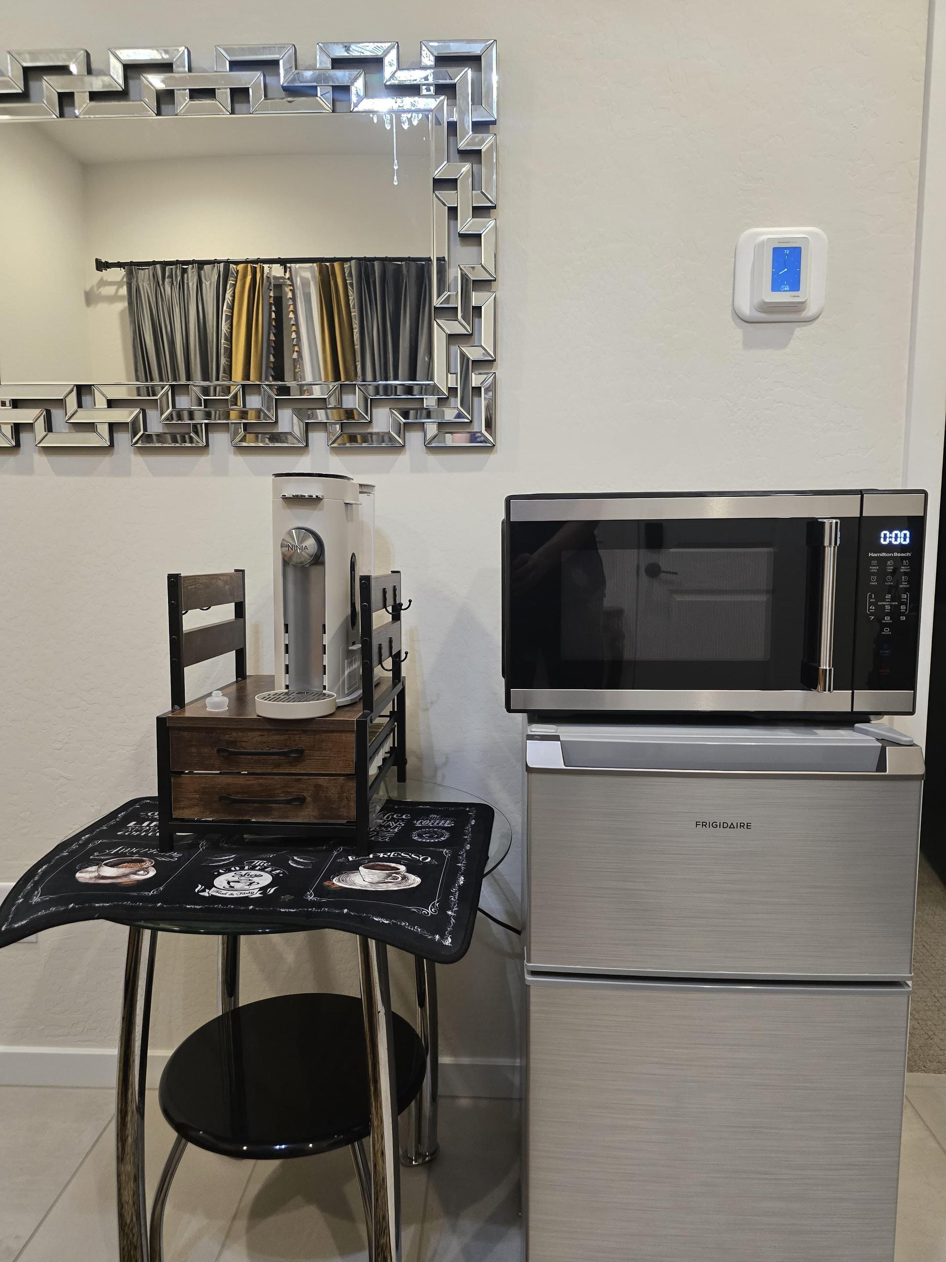 Small kitchenette with fridge, microwave, coffee station, and seating—compact, stylish, and perfect for light meals.
