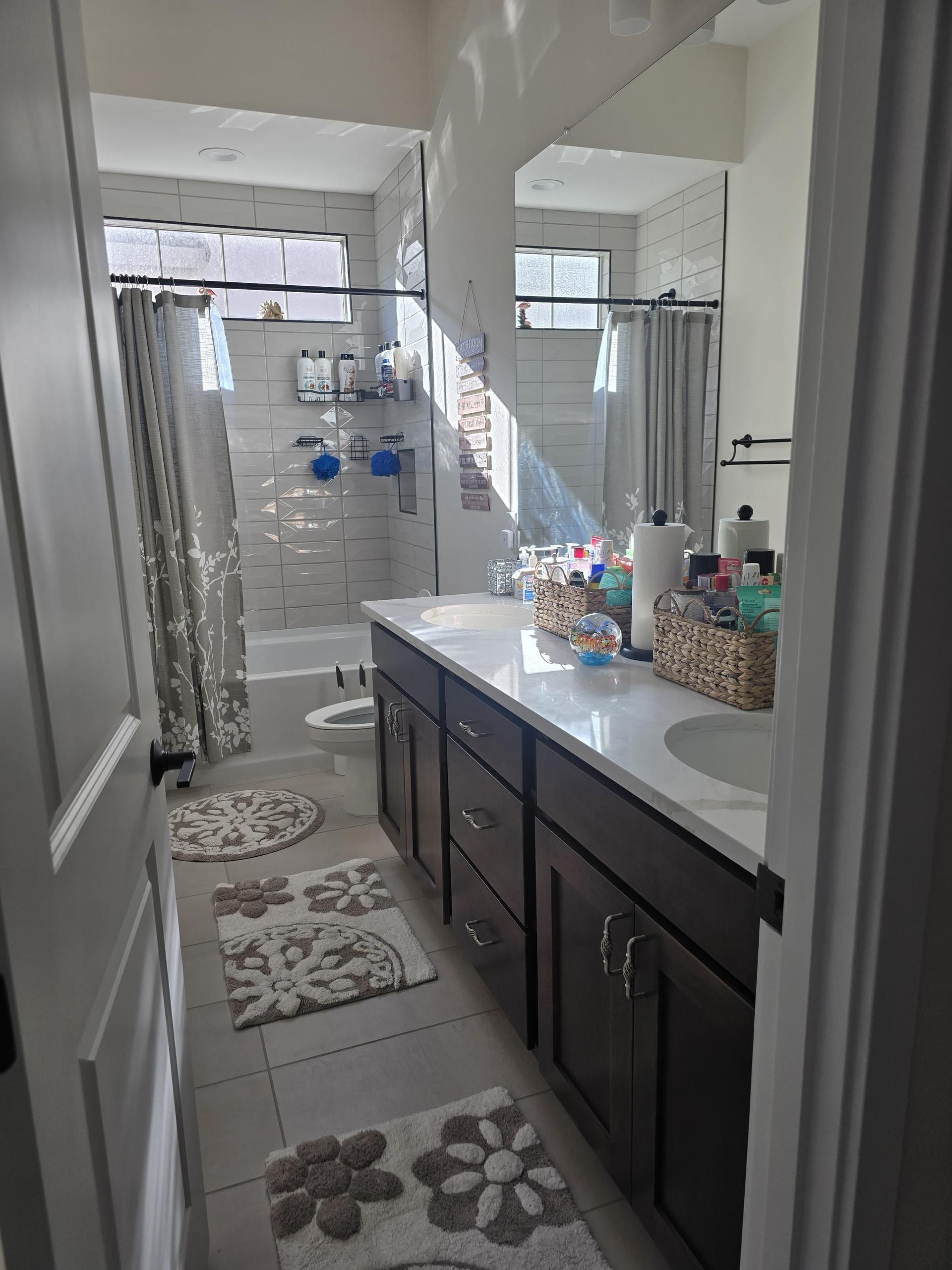 Each sink has a basket with one-time essentials—tonic, toothpaste, mouthwash, wipes, Q-tips, and hygiene basics.