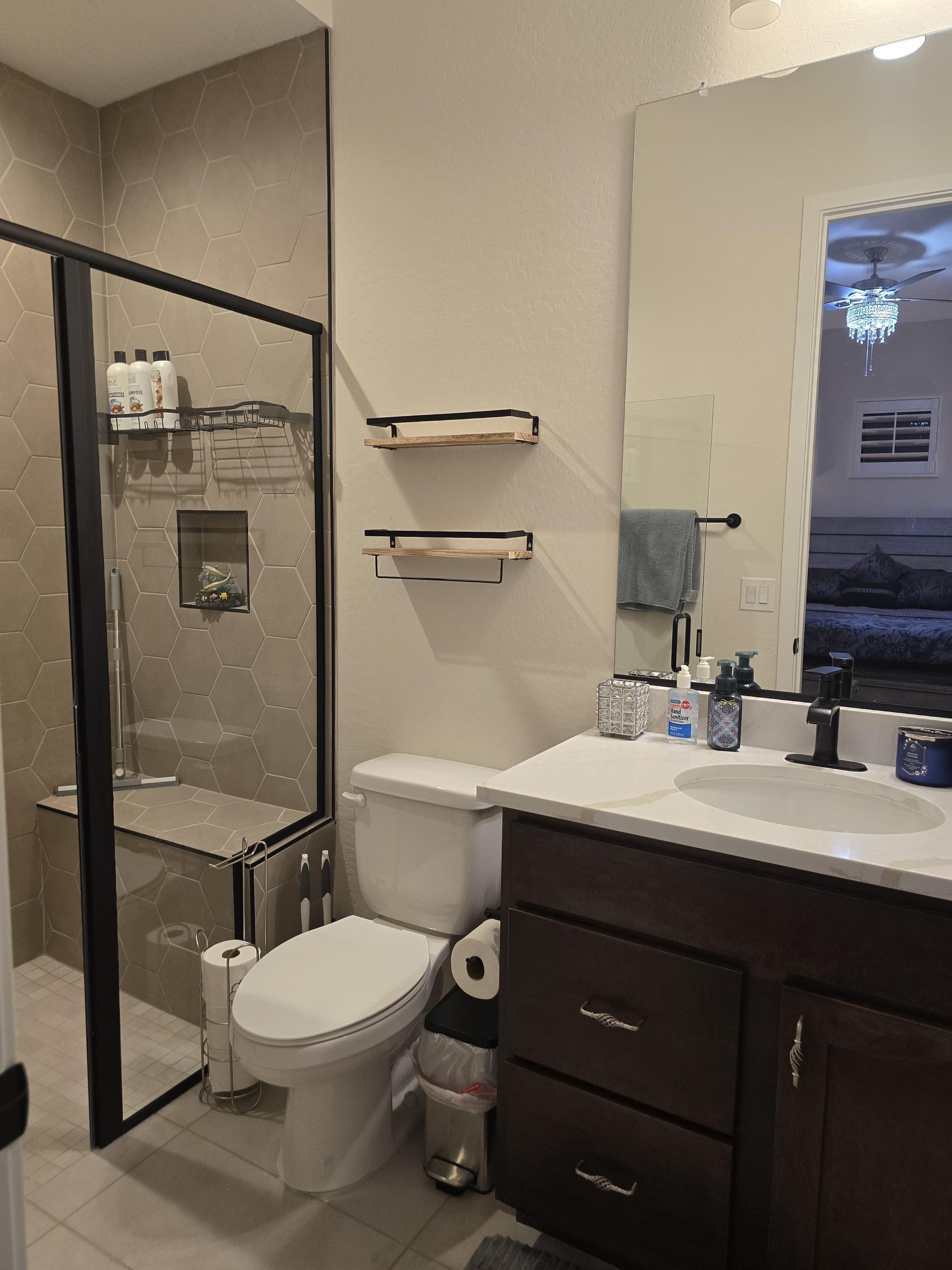 Private bath in Guest Suite A with glass shower, sleek vanity, and a one-time essentials basket for a fresh, easy start.