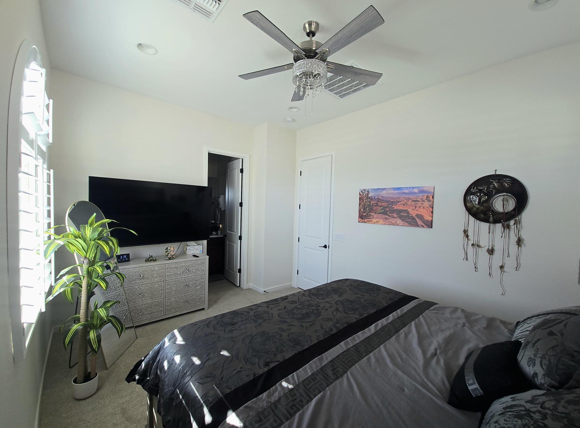 Guest suite features a plush king bed, smart TV, full-height mirror, and calming art, cozy, light-filled, and serene.