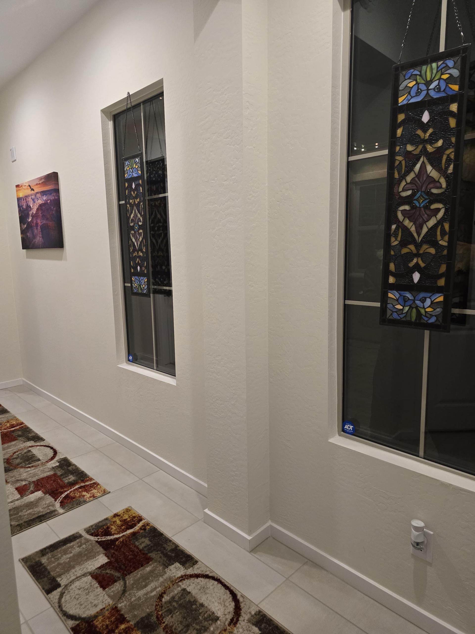Hallway with skylights, stained glass panels, canyon art, abstract rugs, and sleek porcelain tile floor. Bold yet serene.