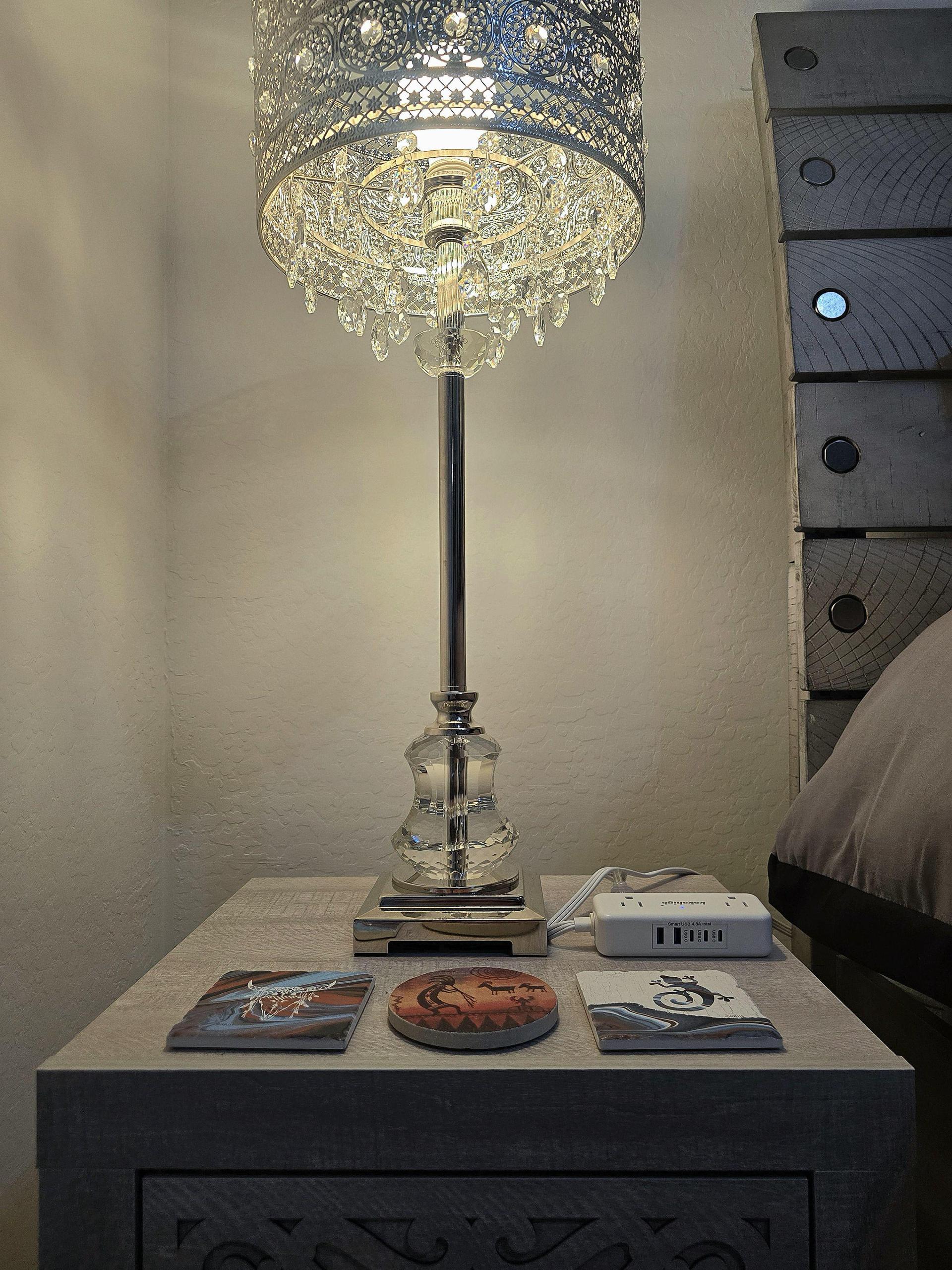 Nightstand with crystal lamp, coasters, and charging ports, USB, USB-C, and standard—ready for all your bedside devices.