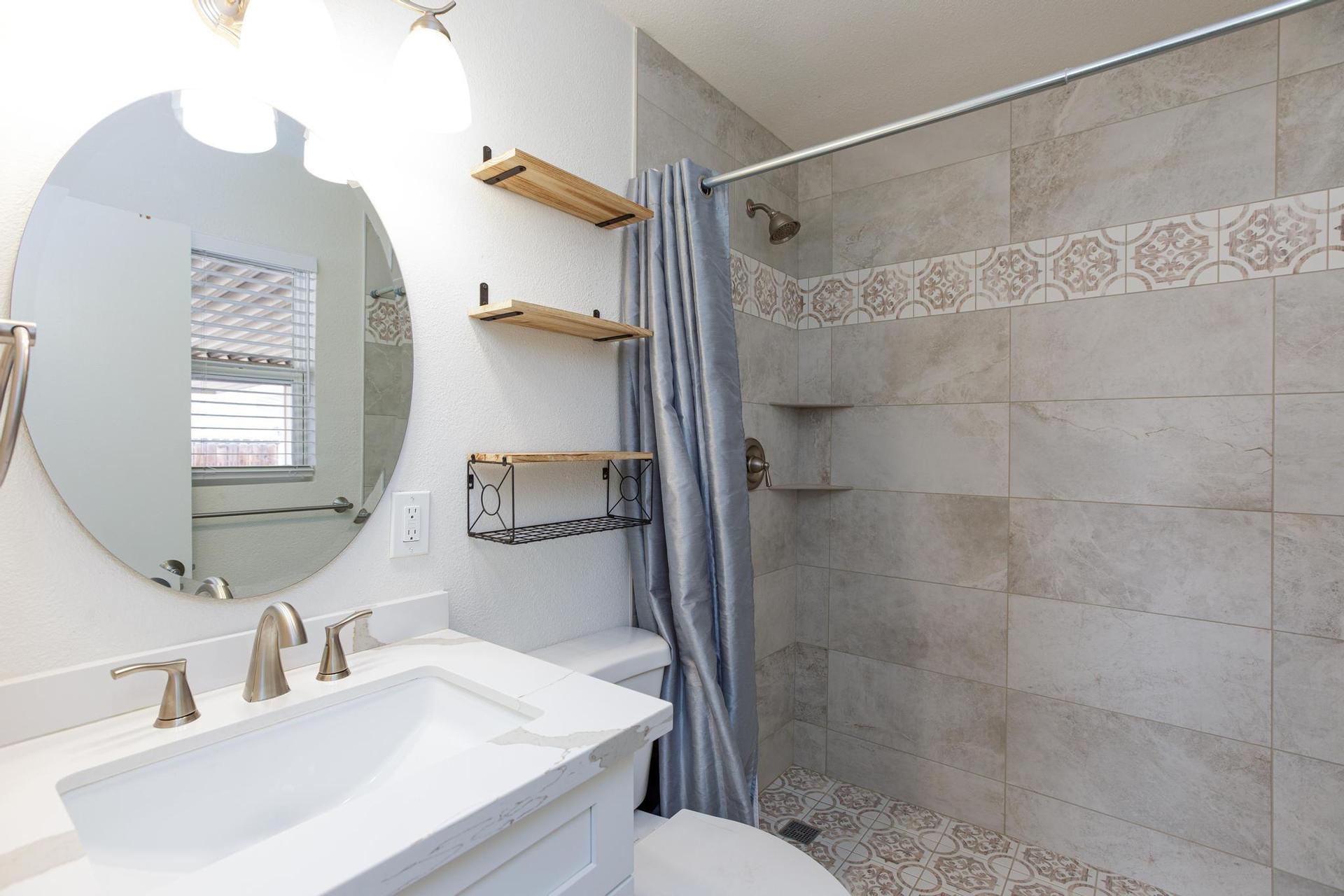 Tile shower with shelves and extra shelves on the wall.