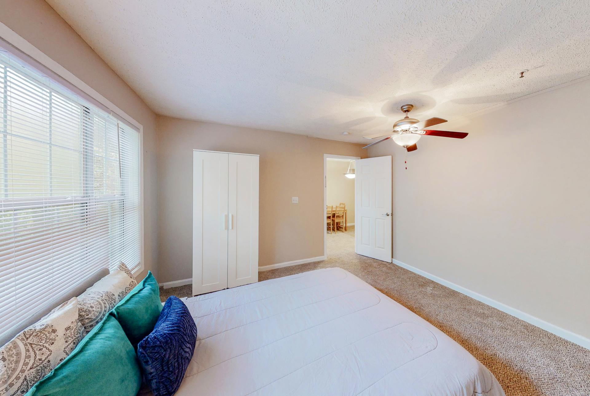 Amazing room equipped with a queen bed, ceiling fan, night stand, vintage lamp and wardrobe.