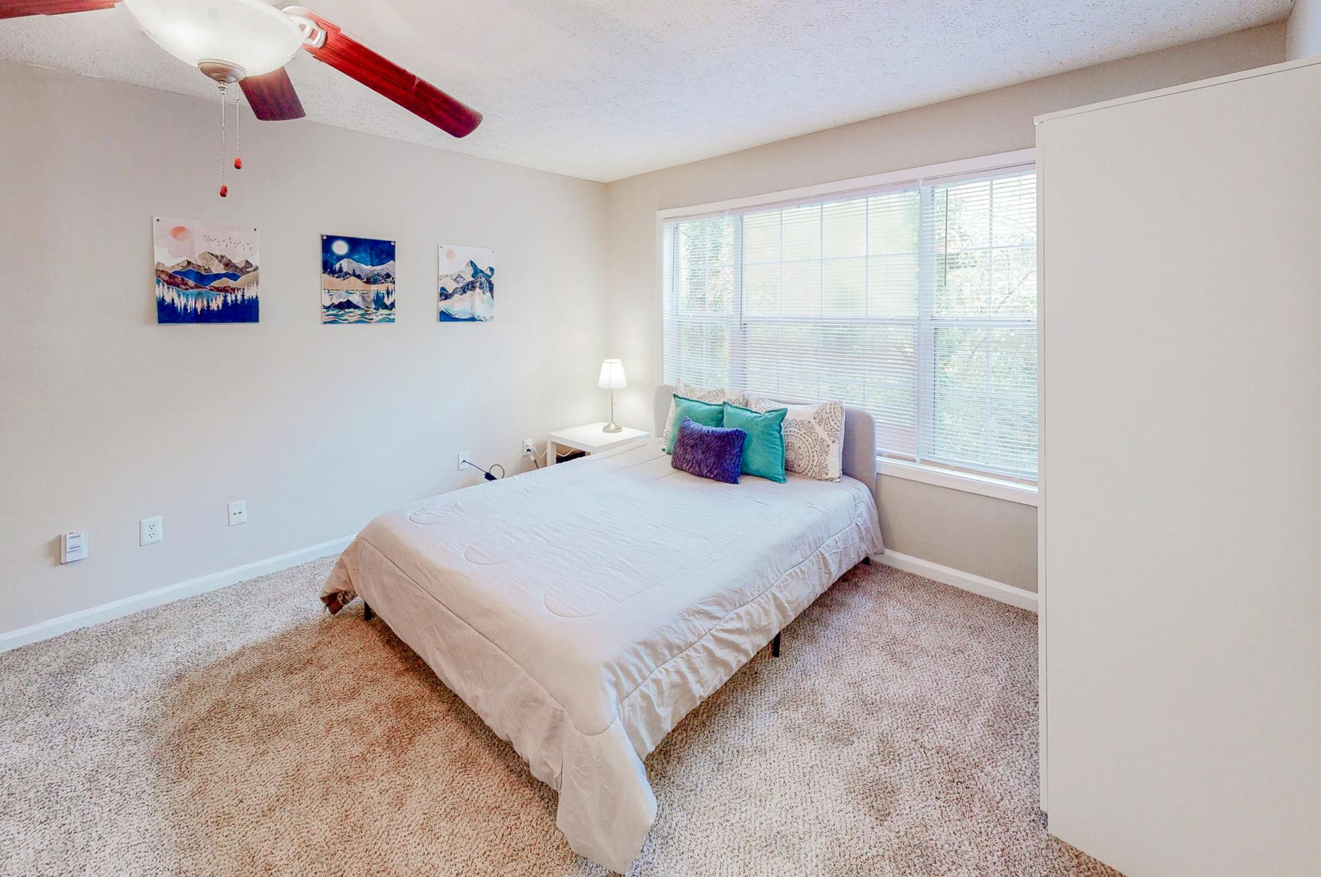 Amazing room equipped with a queen bed, ceiling fan, night stand, vintage lamp and wardrobe.