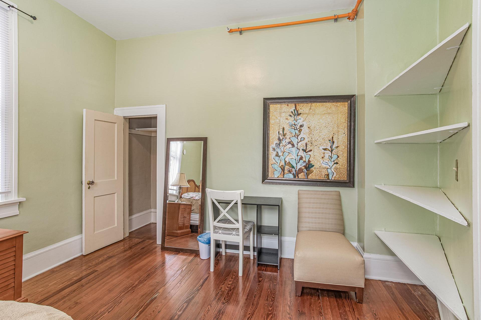 Built in shelving along with closet wall mounted tv, mini fridge sitting chair full size mirror.