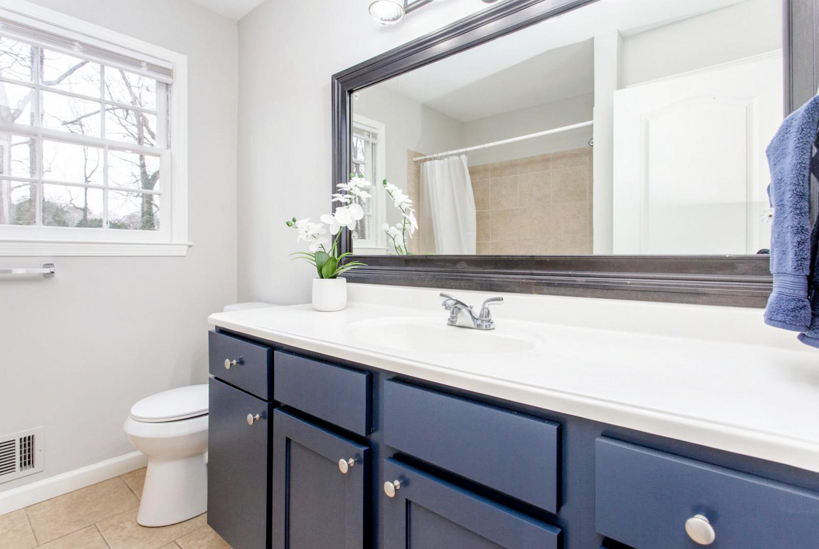 Shared upstairs bath with large vanity and closet for storage.