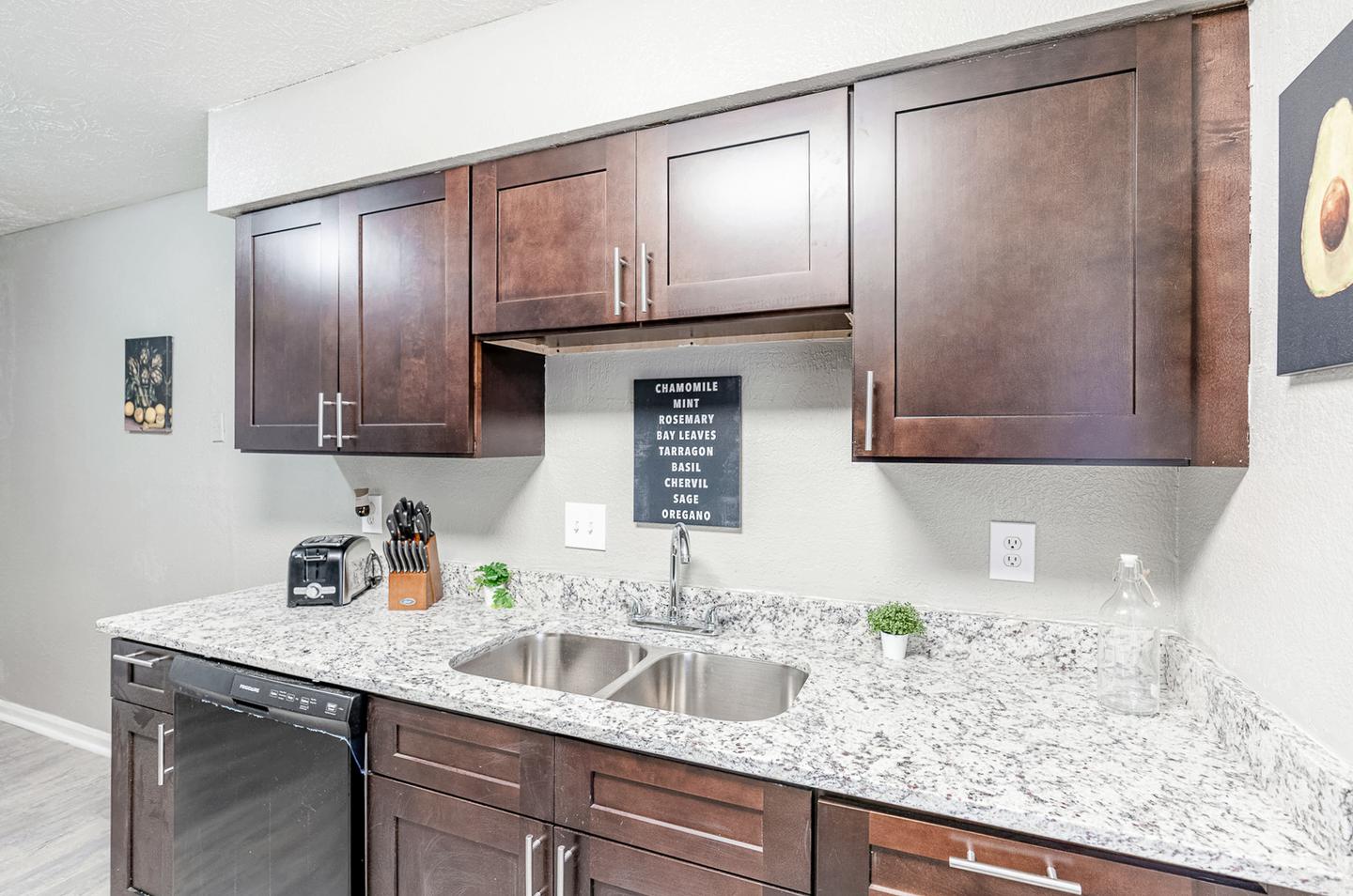 Gorgeous kitchen with granite countertops, cookware, toaster, utensils, and black appliances.