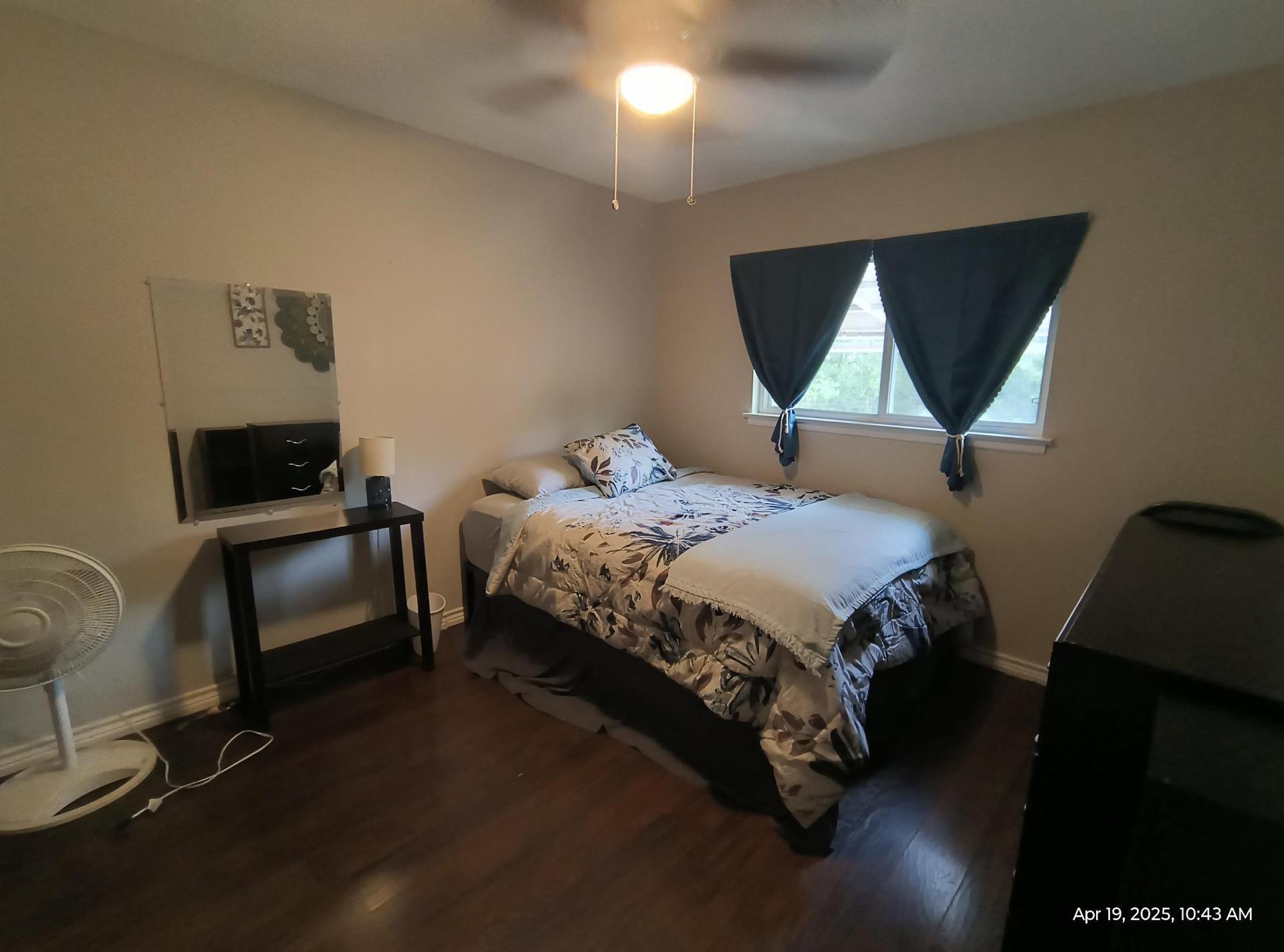 Queen bed with space underneath for storage, end table, personal mirror, personal fan.