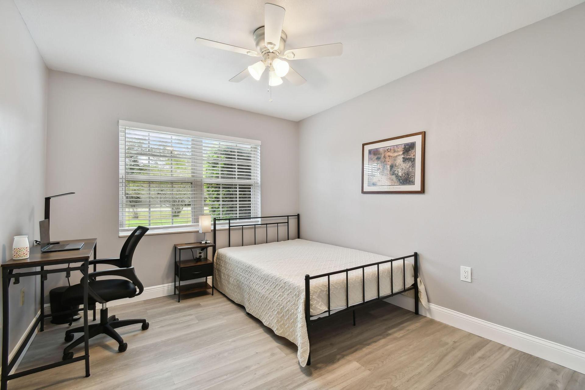 Full size cozy bed, with end table, light, office desk, chair and light as well as storage container under the bed.