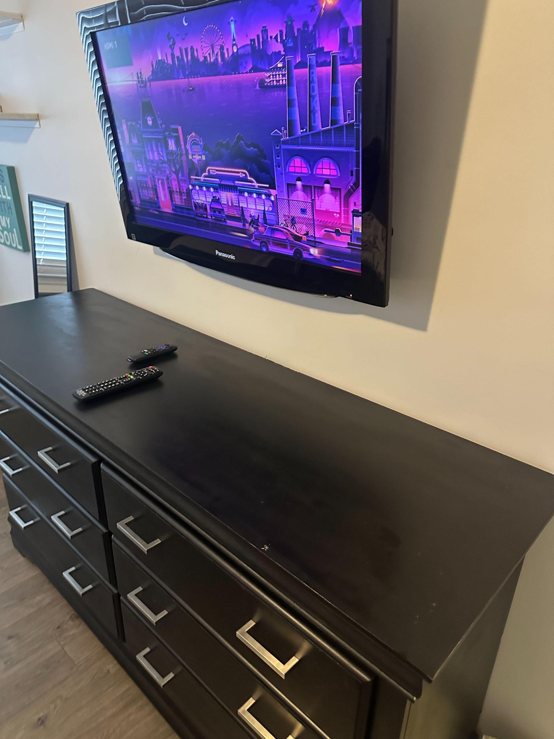 Primary bedroom has a large Smart TV with two remotes and dresser.