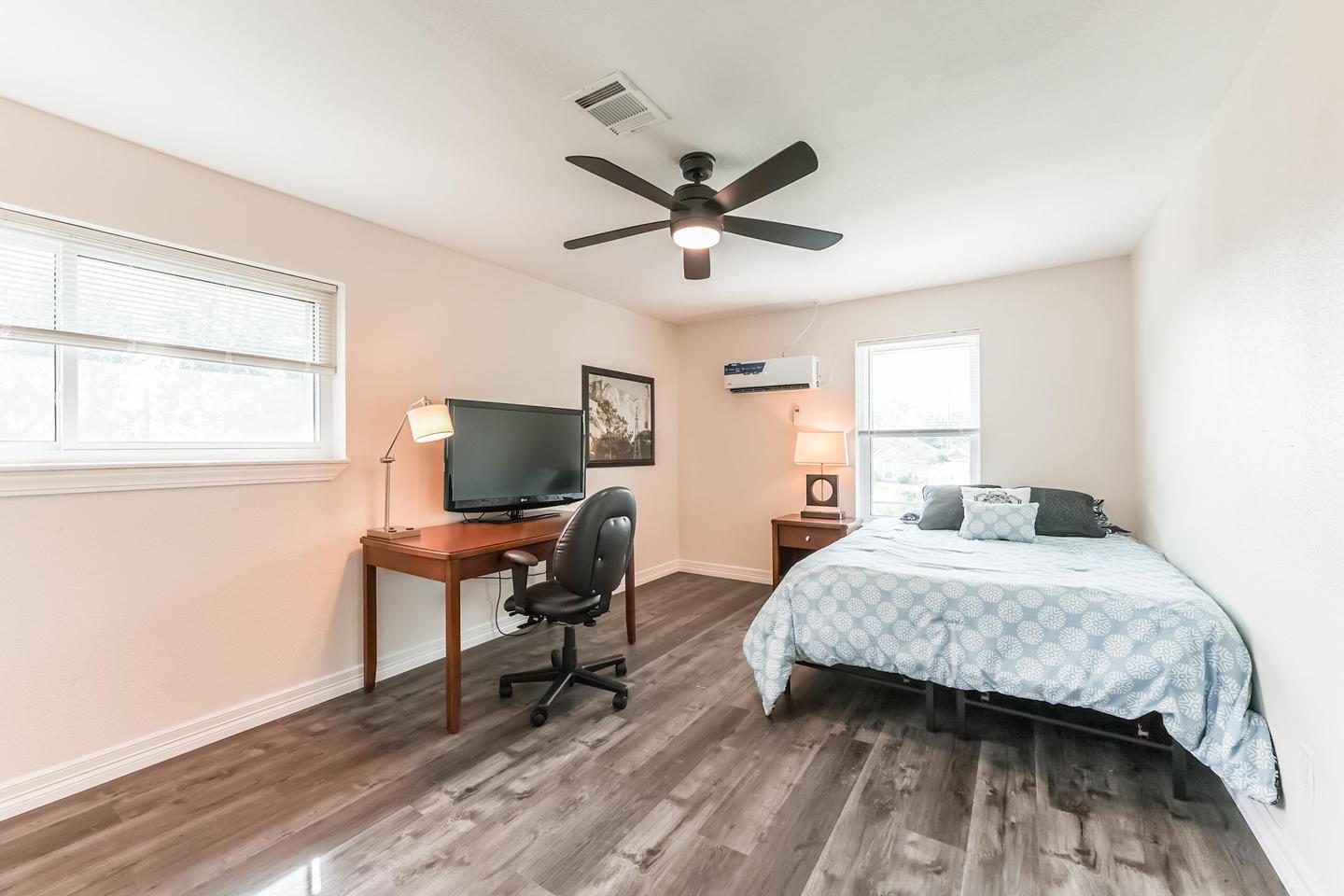 Upstairs room with minisplit AC, queen bed, hybrid mattress, night stand, full length mirror, and desk with chair and TV.