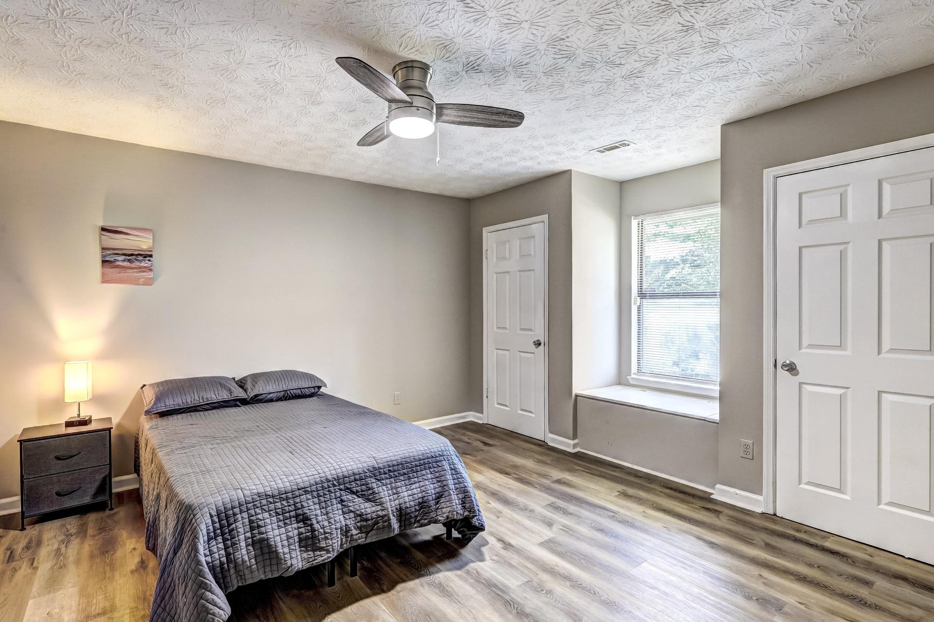 Queen bed, ceiling fan, and sit in window with extra storage