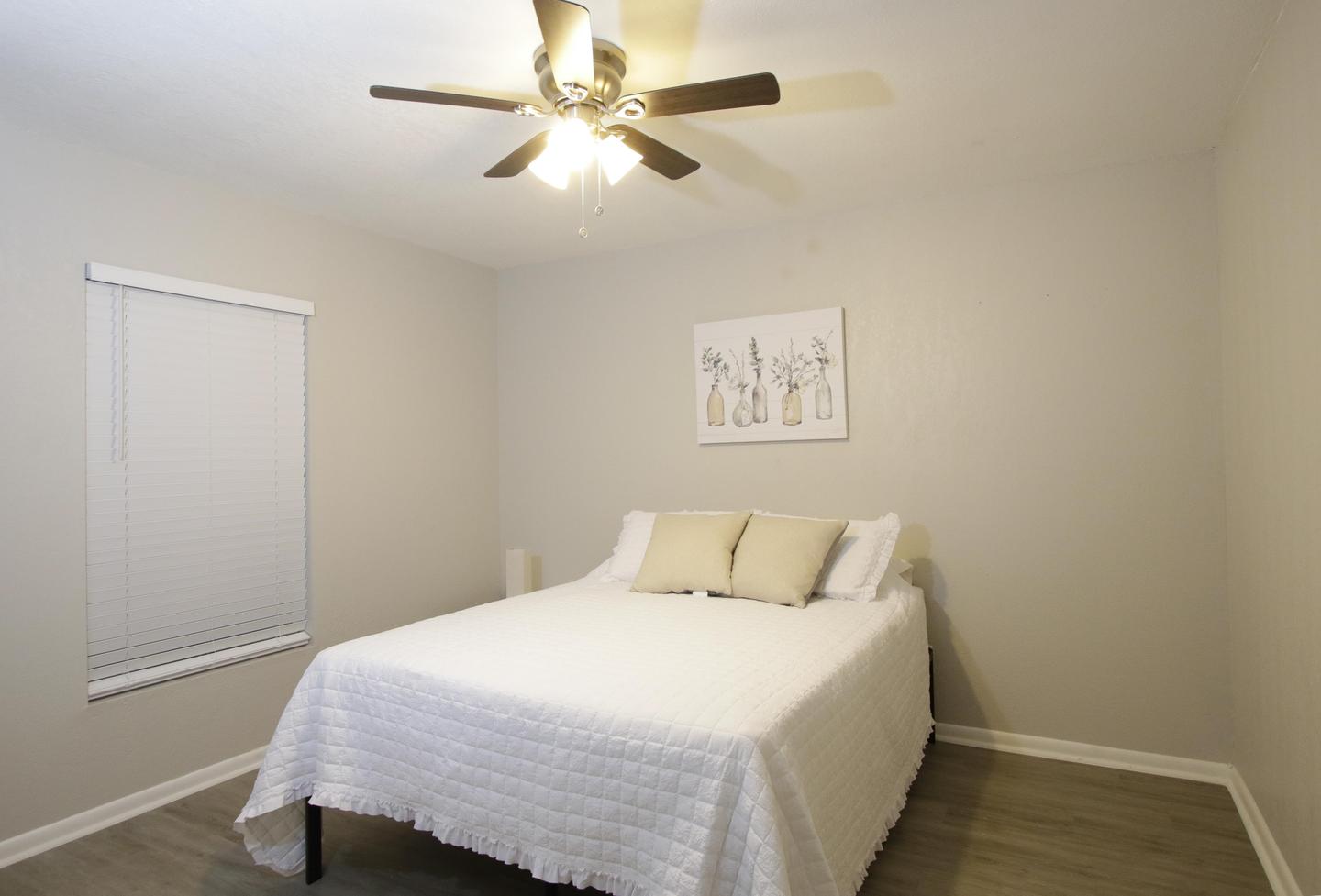 Bedroom 7 with queen bed, large walk-in closet, ceiling fan, walk-in closet, nightstand, wall art and lamp.