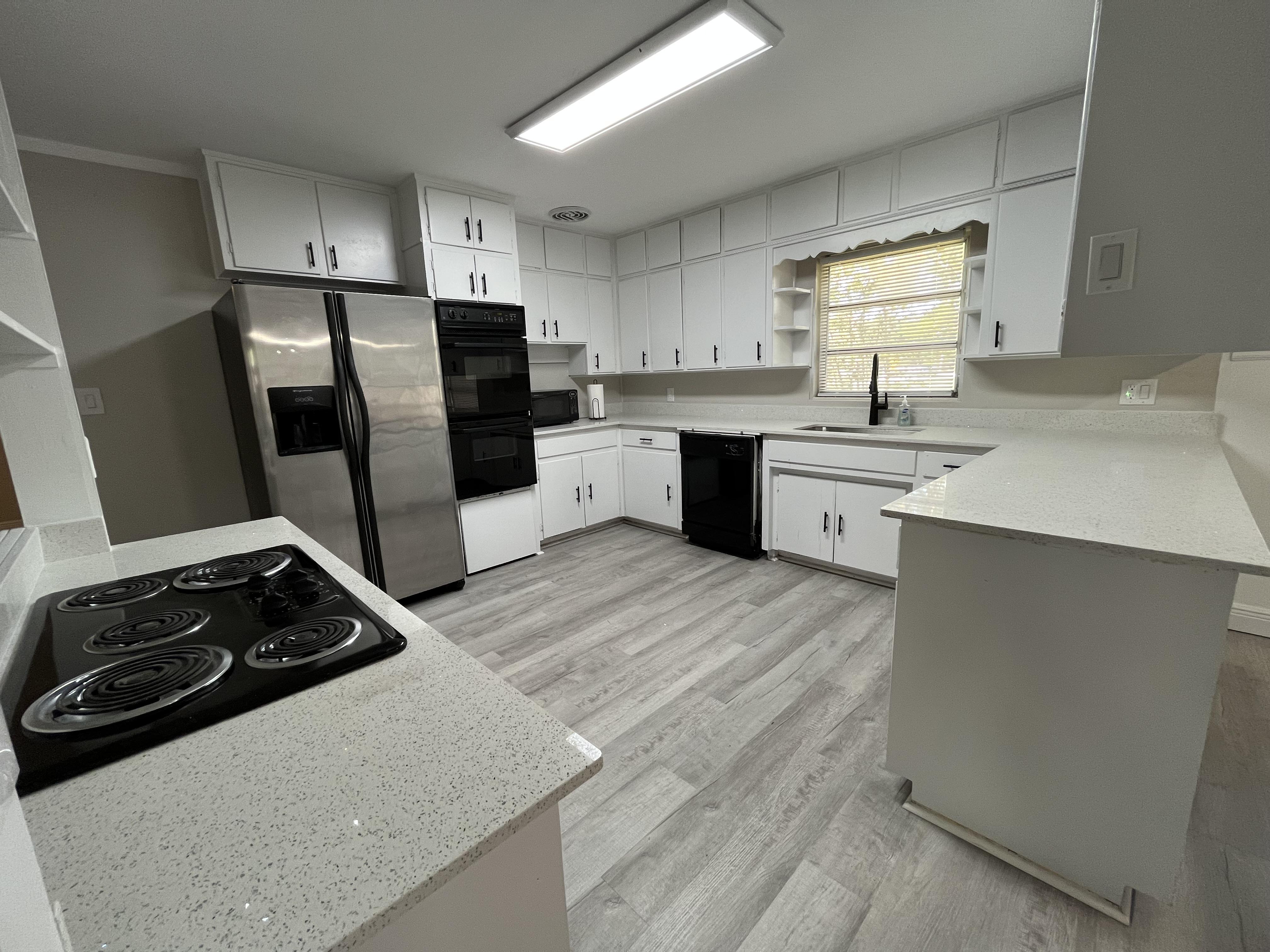 Large, clean kitchen with stainless steel fridge, double ovens, stovetop, dishwasher, and lots of storage space!